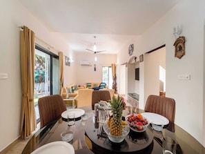 A dining area with a round table, chairs, and a fruit bowl. - DanCenter Trizi Villa 4BHK with Pvt Pool (Lonavala)