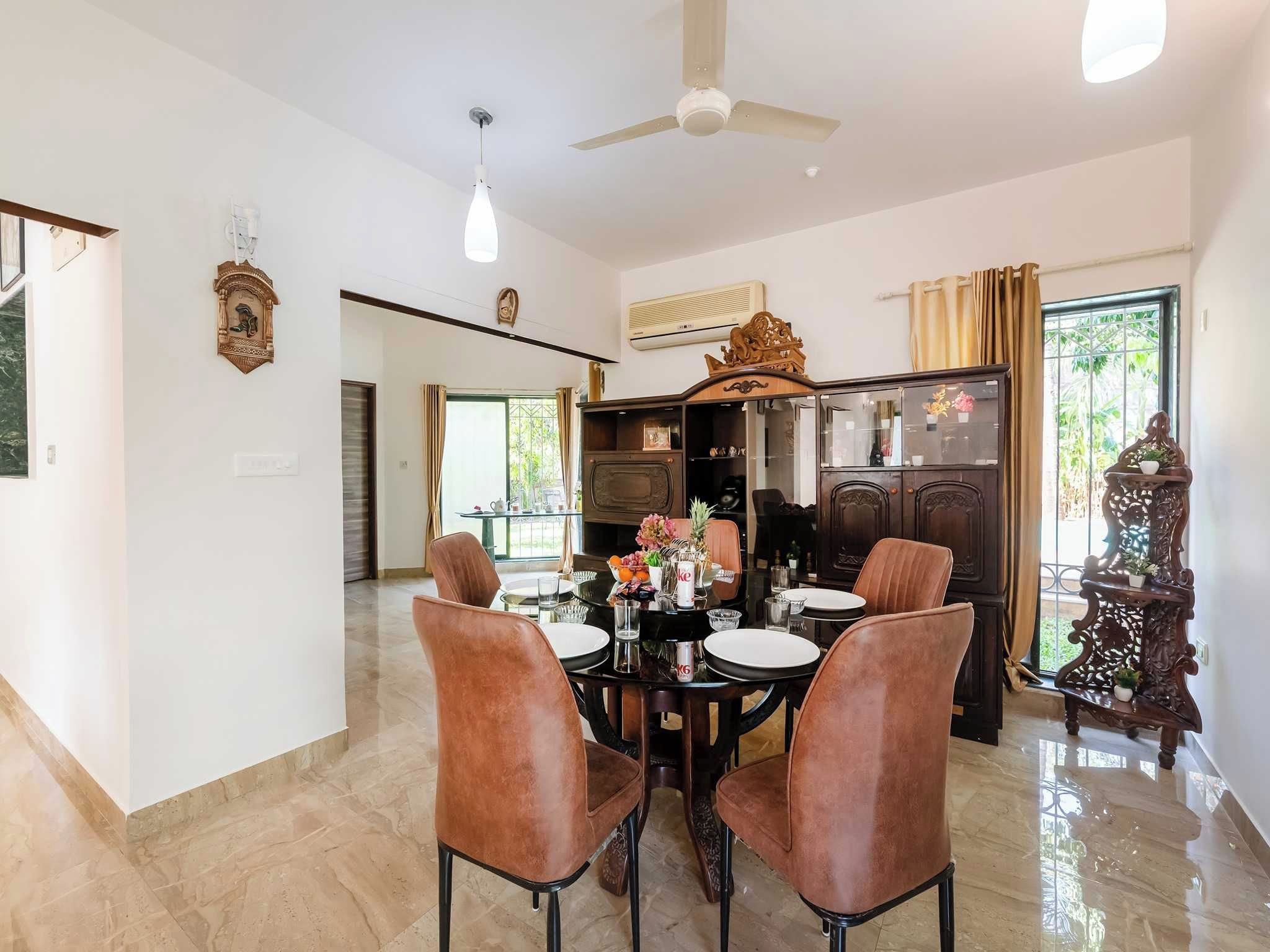 A dining area with a round table, four chairs, and a ceiling fan.