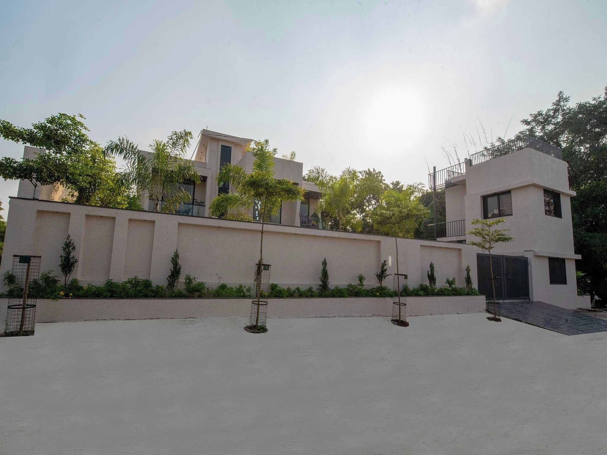 A modern building with a flat roof, a gated entrance, and a paved courtyard.