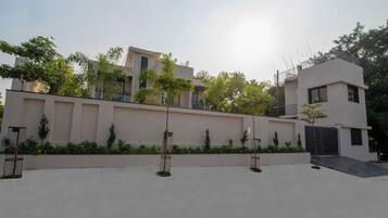 A modern building with a flat roof, a gated entrance, and a paved courtyard.