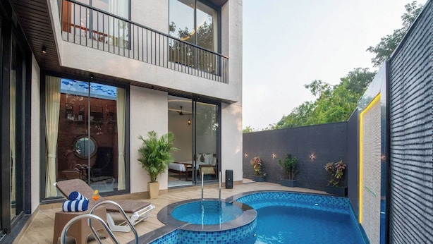 Uma casa moderna de dois andares com piscina, área de estar externa e varanda.