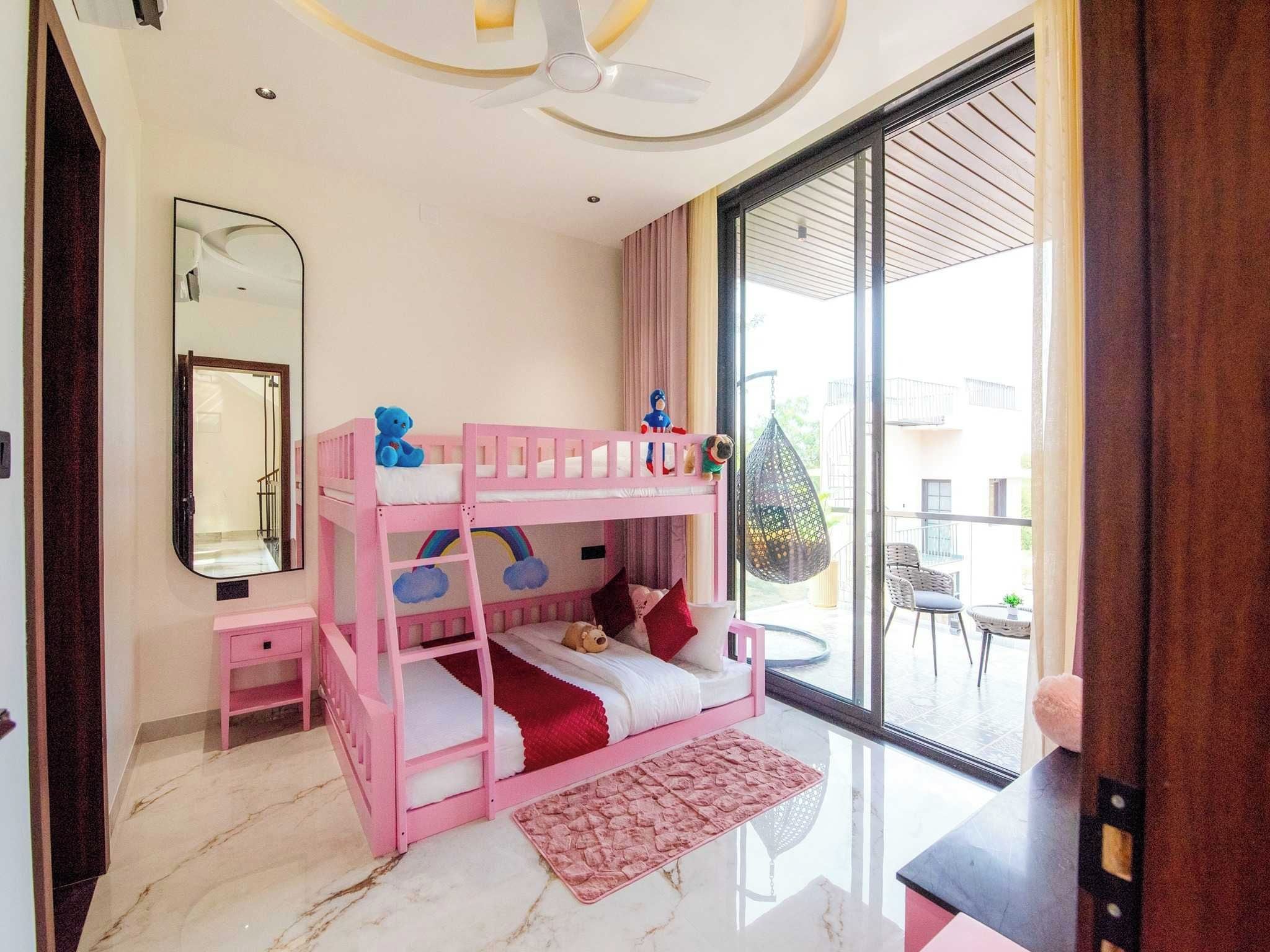 Una cama litera infantil con juguetes, una mesita de noche pequeña, un espejo y vistas al exterior.