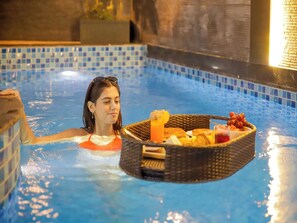 Pessoa em piscina com cesta contendo alimentos.
