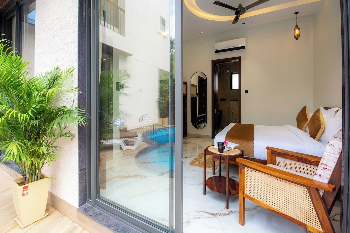A modern hotel room with a glass door leading to a pool, a ceiling fan, and a small table with a book and a cup.