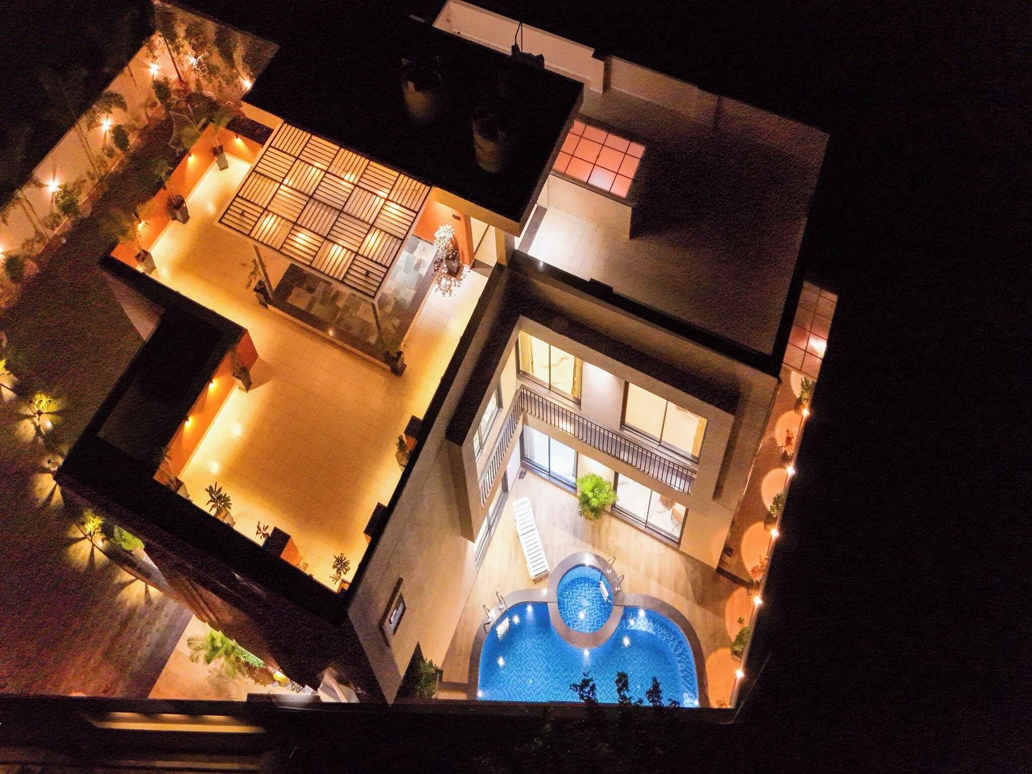 Un hotel con piscina en la azotea, mobiliario exterior y un interior bien iluminado.