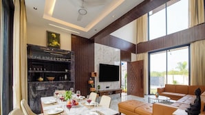 Sala de estar moderna com área de jantar, televisão de tela plana e uma grande janela com vista para o exterior.