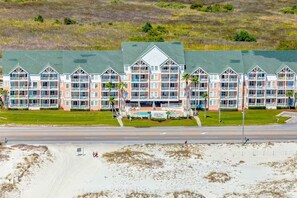 Ein mehrstöckiges Hotel mit Innenhof, Balkonen und Blick auf den Strand.