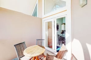 Ein Balkon mit Tisch und Stühlen, eine Glastür zum Innenbereich und Blick ins Innere.