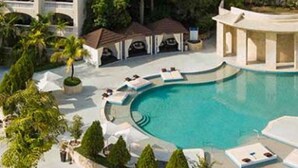 Resort com uma piscina grande, espreguiçadeiras e um edifício com várias varandas.