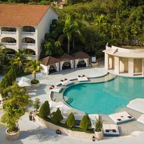 Un complexe hôtelier doté d’une grande piscine, de chaises longues et d’un bâtiment comportant de nombreux balcons.