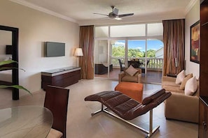 Un salon moderne avec un canapé, un banc, un téléviseur et un balcon agrémenté de rideaux.