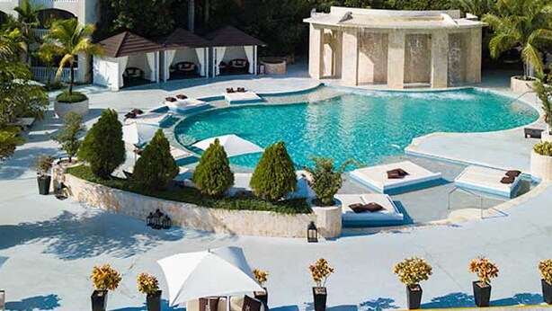 Área de piscina com espreguiçadeiras e um gazebo.