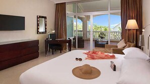 Quarto de hotel com uma cama grande, escrivaninha, cadeira, televisão e varanda com vista.