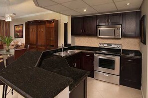 Une cuisine moderne avec des meubles de couleur sombre, des appareils électroménagers en acier inoxydable et un plan de travail en granit.