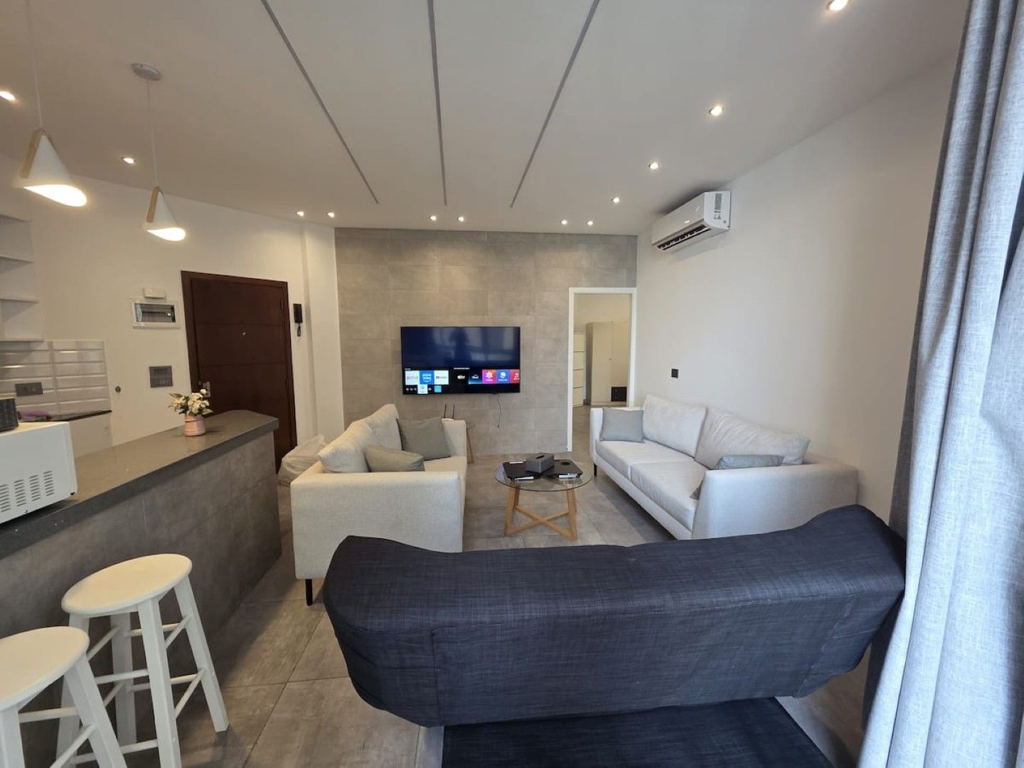 A modern living room with a sofa, a coffee table, and a TV mounted on the wall.