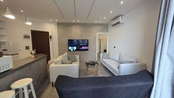A modern living room with a sofa, a coffee table, and a TV mounted on the wall.