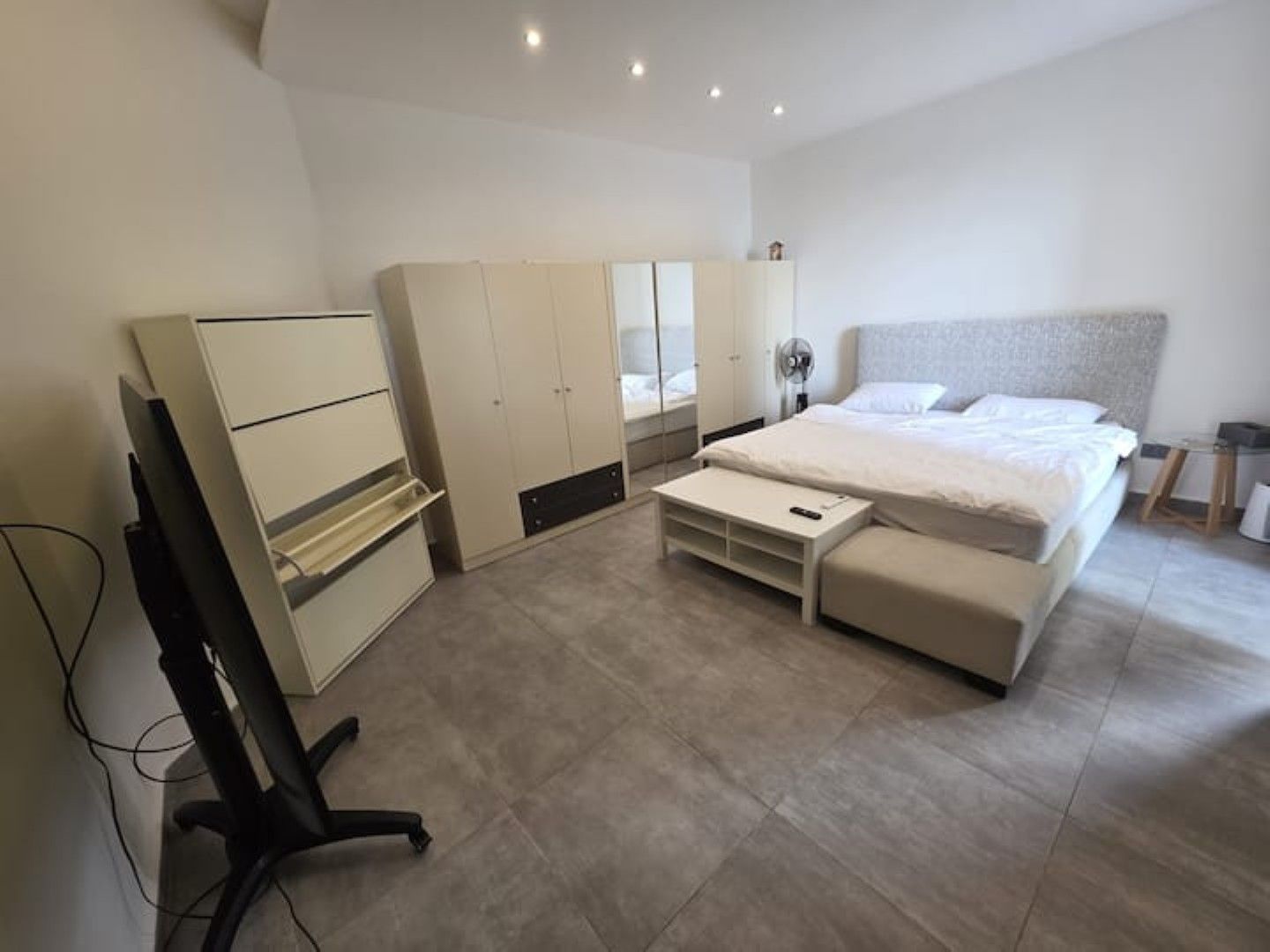 A bedroom with a bed, a desk, and a wardrobe.