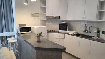 A modern kitchen with white cabinets, a microwave, a built-in oven, and a sink.