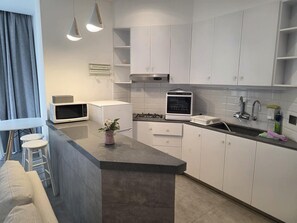 Eine moderne Küche mit weißen Schränken, einer Mikrowelle, einem Backofen und einem Spülbecken.