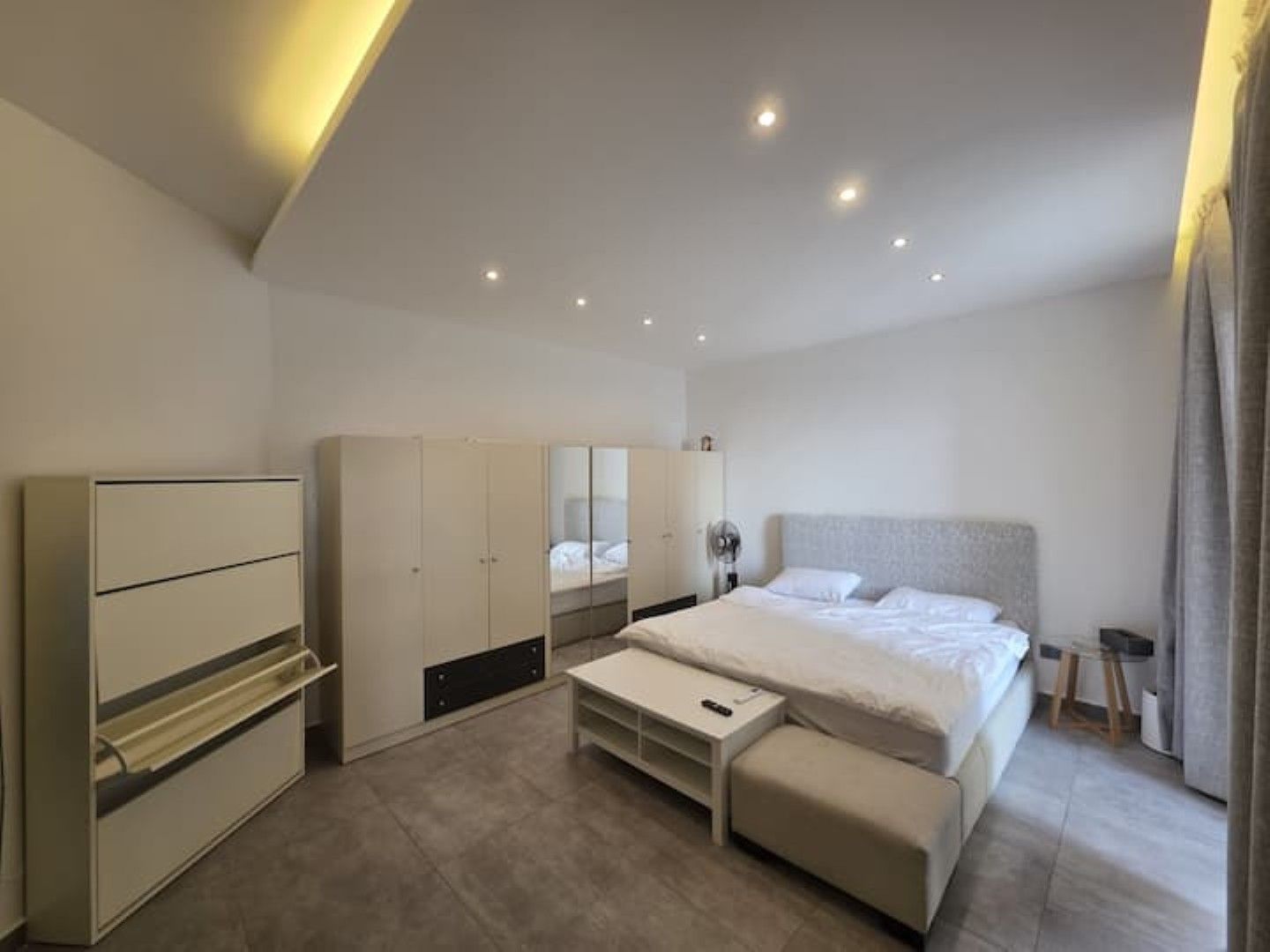 A modern bedroom with a bed, bedside tables, a wardrobe, and a mirror.