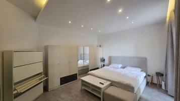 A modern bedroom with a bed, bedside tables, a wardrobe, and a mirror.