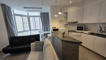 A modern kitchen with white cabinets, a central island, and a dining area with a sofa and chairs.