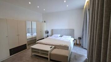 A modern bedroom with a bed, a wardrobe, a bedside table, and a mirror.
