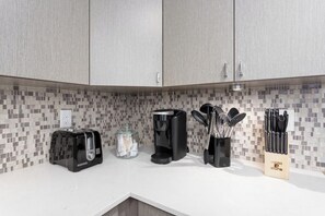 A kitchen with a toaster, coffee maker, and utensil holder on the counter.
