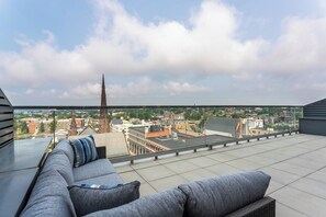 A rooftop terrace with a view of a cityscape, including a prominent church spire.