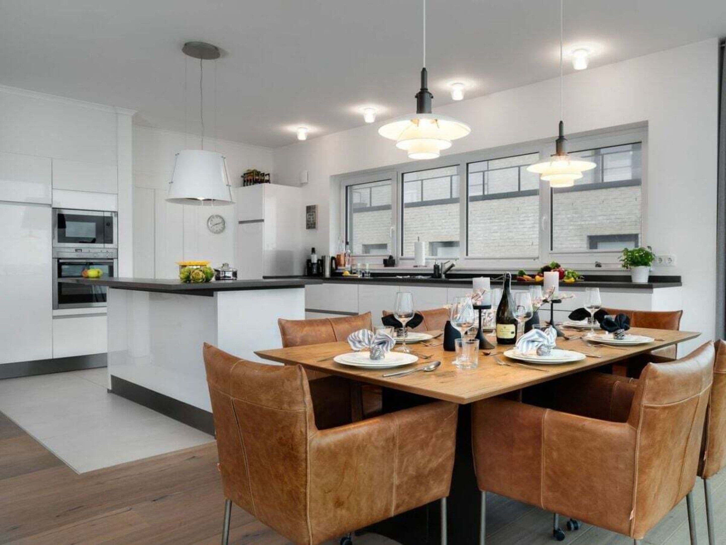 A modern kitchen with white cabinetry, a central island, and pendant lighting.