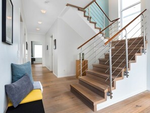 A modern interior with a wooden staircase, a bench with cushions, and a hallway leading to another room. - Villa Blue Horizon (Kappeln)