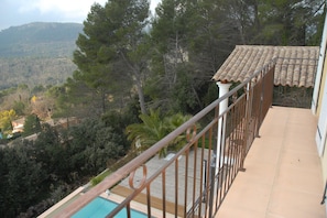 A balcony with a view of a mountainous landscape, a swimming pool, and a tiled roof. - Holiday Home With Pool and Natural View (Bagnols-en-Foret)