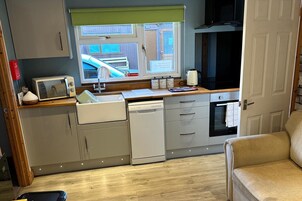 Cocina compacta con ventana, microondas, fregadero y lavavajillas.
