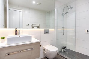 A modern bathroom with a glass-enclosed shower, a white sink, and a toilet. - Solara by Homello (Auckland)