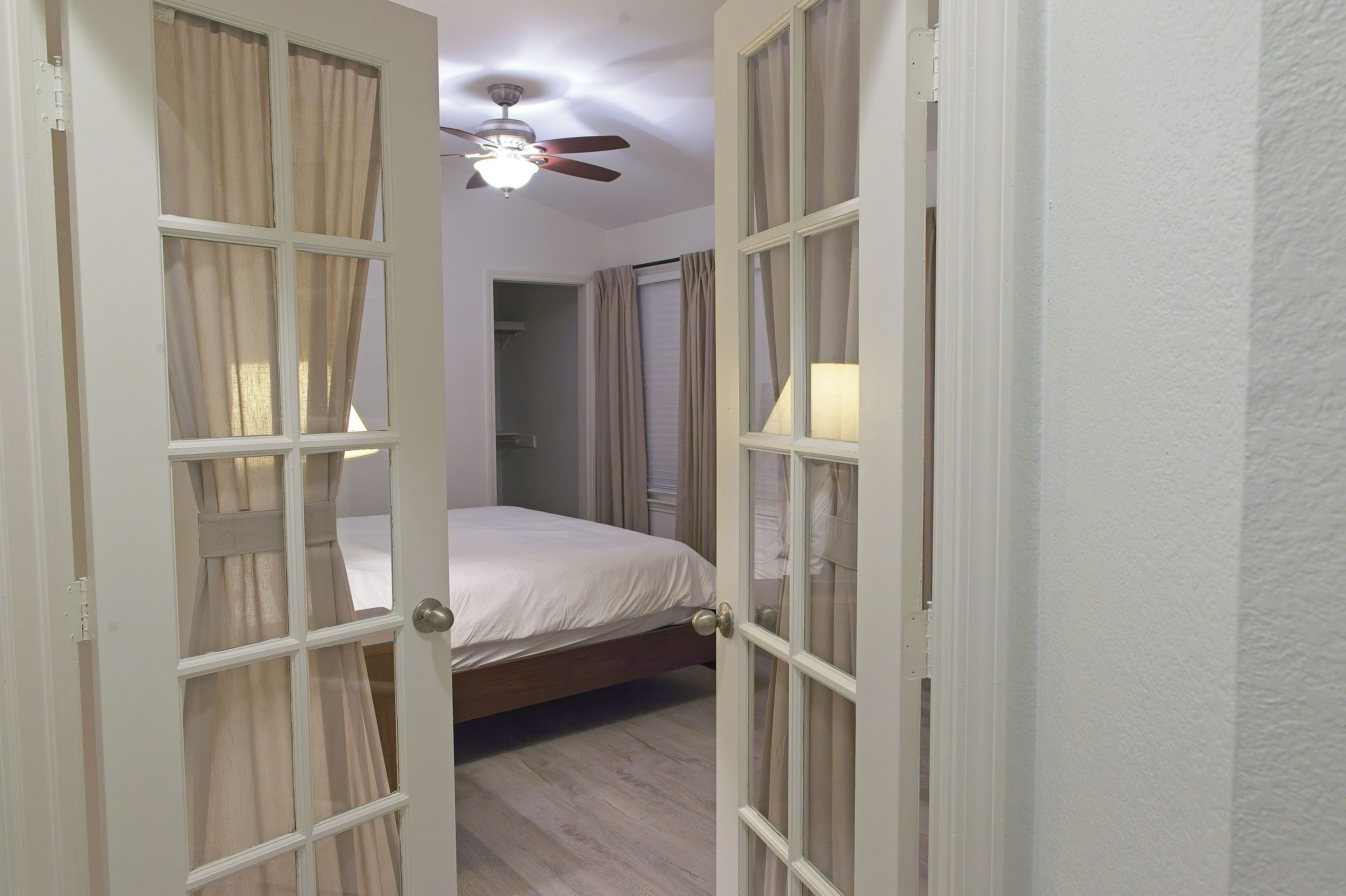 A bedroom with a bed, a ceiling fan, and a window with curtains.