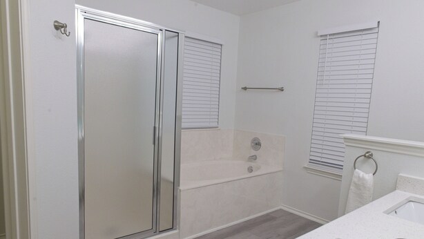 Une salle de bain avec une douche à parois de verre, une baignoire et un lavabo muni d’un porte-serviettes.
