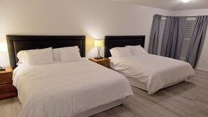 Une chambre d’hôtel avec deux lits, une table de chevet, une lampe et une fenêtre avec des rideaux.