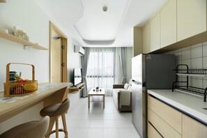 A modern kitchen with a built-in stove, a dining area with a table and chairs, and a living room with a sofa and a TV. - Kamala - Nature View from Above (Tambon Kamala)