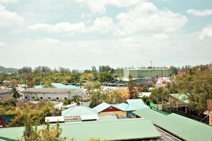 A residential area with houses, some with green roofs, and a large industrial building in the background. - Kamala - Nature View from Above (Tambon Kamala)