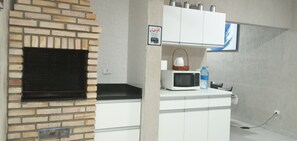 Een kitchenette met een bakoven, witte kastjes, een magnetron en een waterfles.
