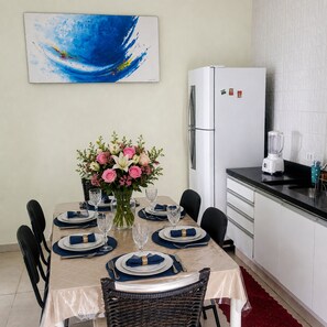 Zona de menjador amb taula preparada per a sis, nevera i taulell de cuina.