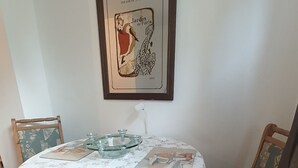 A dining table with a floral tablecloth, two chairs with patterned upholstery, a framed picture above the table, and a small table lamp. - Cozy vacation rental near the harbor (Wismar)