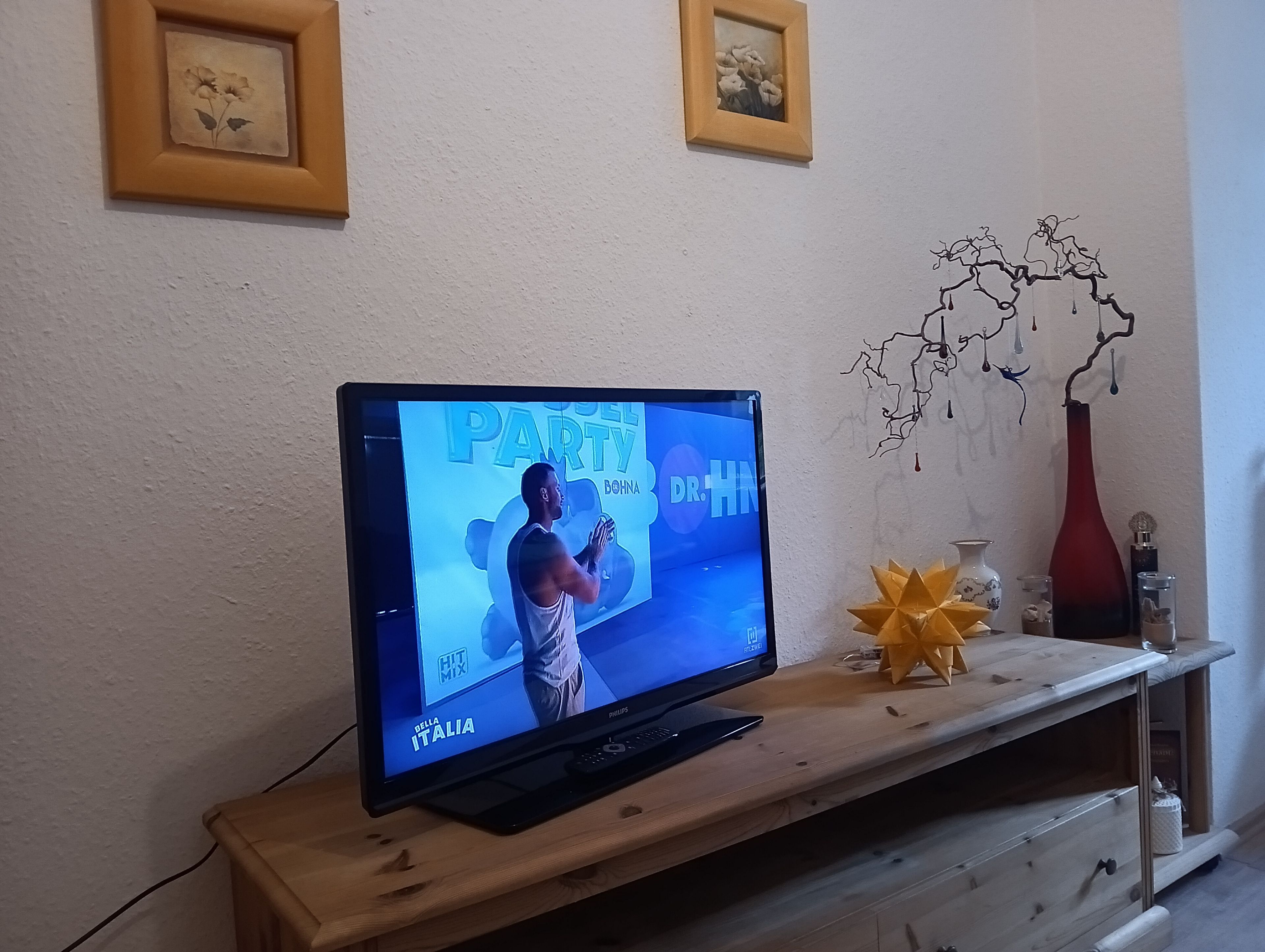 A television on a wooden stand displaying a sports event.