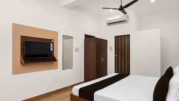 A bedroom with a bed, a television mounted on the wall, a wardrobe, and a ceiling fan.