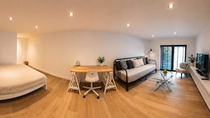 Un espacio habitable moderno y abierto con cama, sofá, mesa de comedor y televisor.