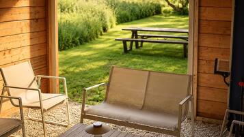 Een houten hut met een terras, compleet met een bank, een tafel en een stoel.