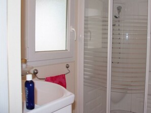 A bathroom with a white sink, a red towel, and a glass shower enclosure. - Relaxed Seaside Escape in France (Hyères)