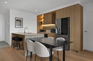 Eine moderne Küche mit Kochinsel, Barhocker und Kühlschrank.