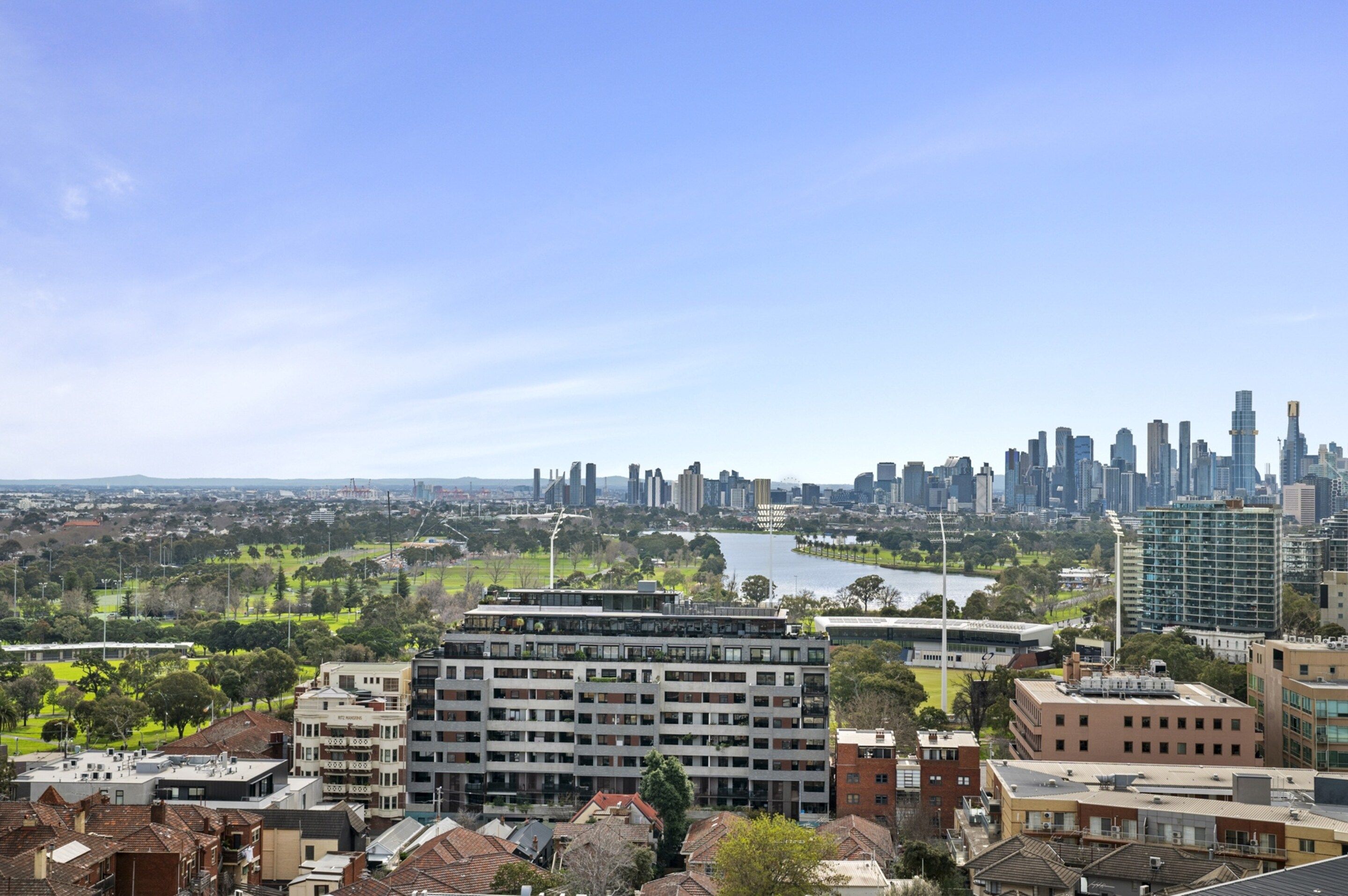 A cityscape with modern buildings, a river, and green spaces.