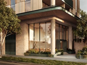 Een modern gebouw met grote glasramen, een bakstenen gevel en een groene luifel.